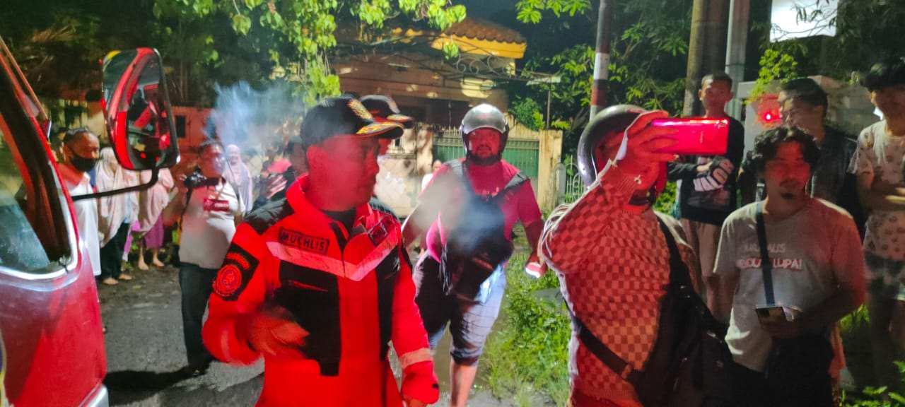 Tim Damkar Makassar dalam proses evakuasi pria hendak lompat dari atap rumah warga. (Dok/Damkar Makassar).